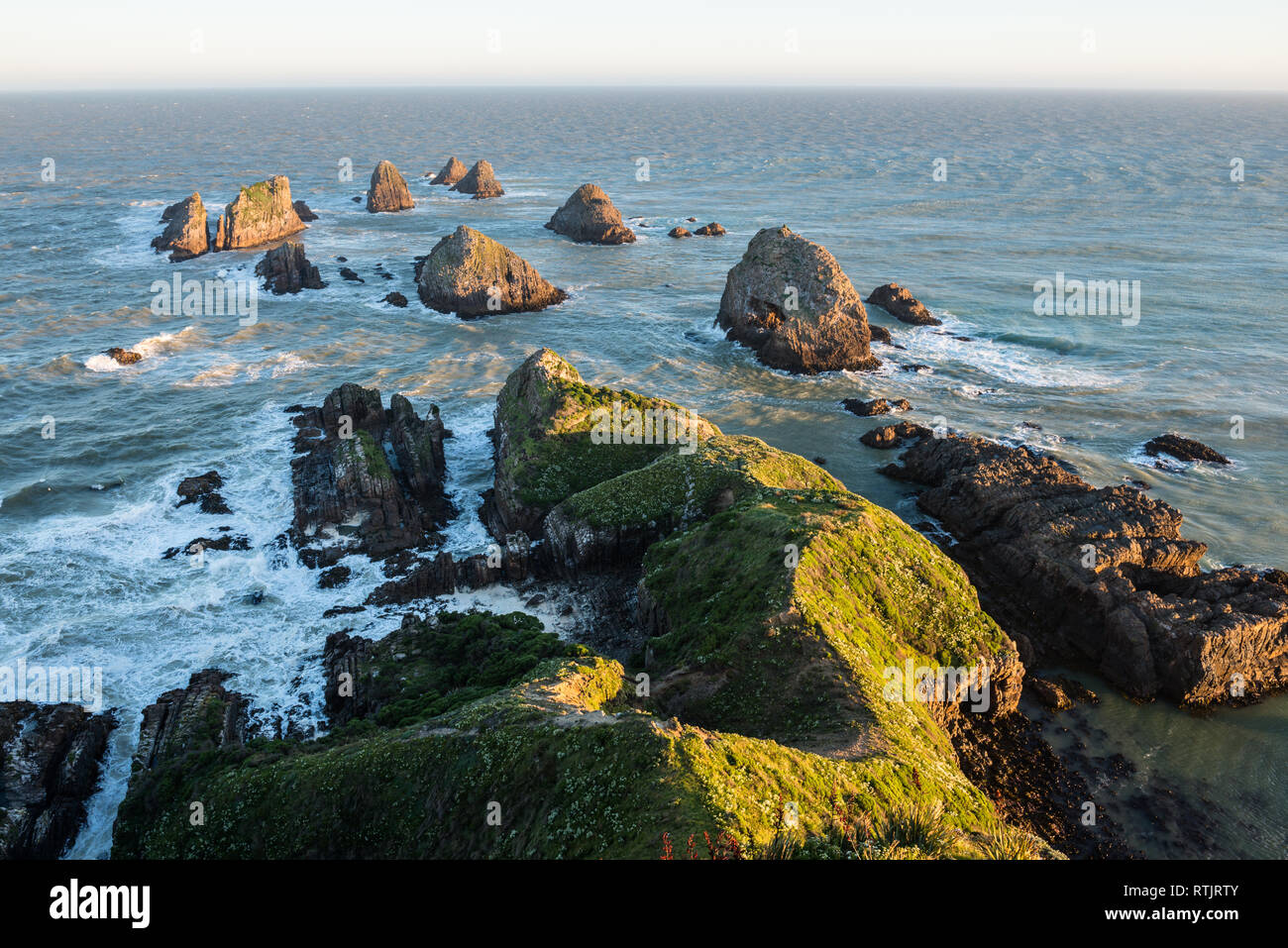 Le soleil qui éclaire les rochers et vagues de Nugget Point Banque D'Images