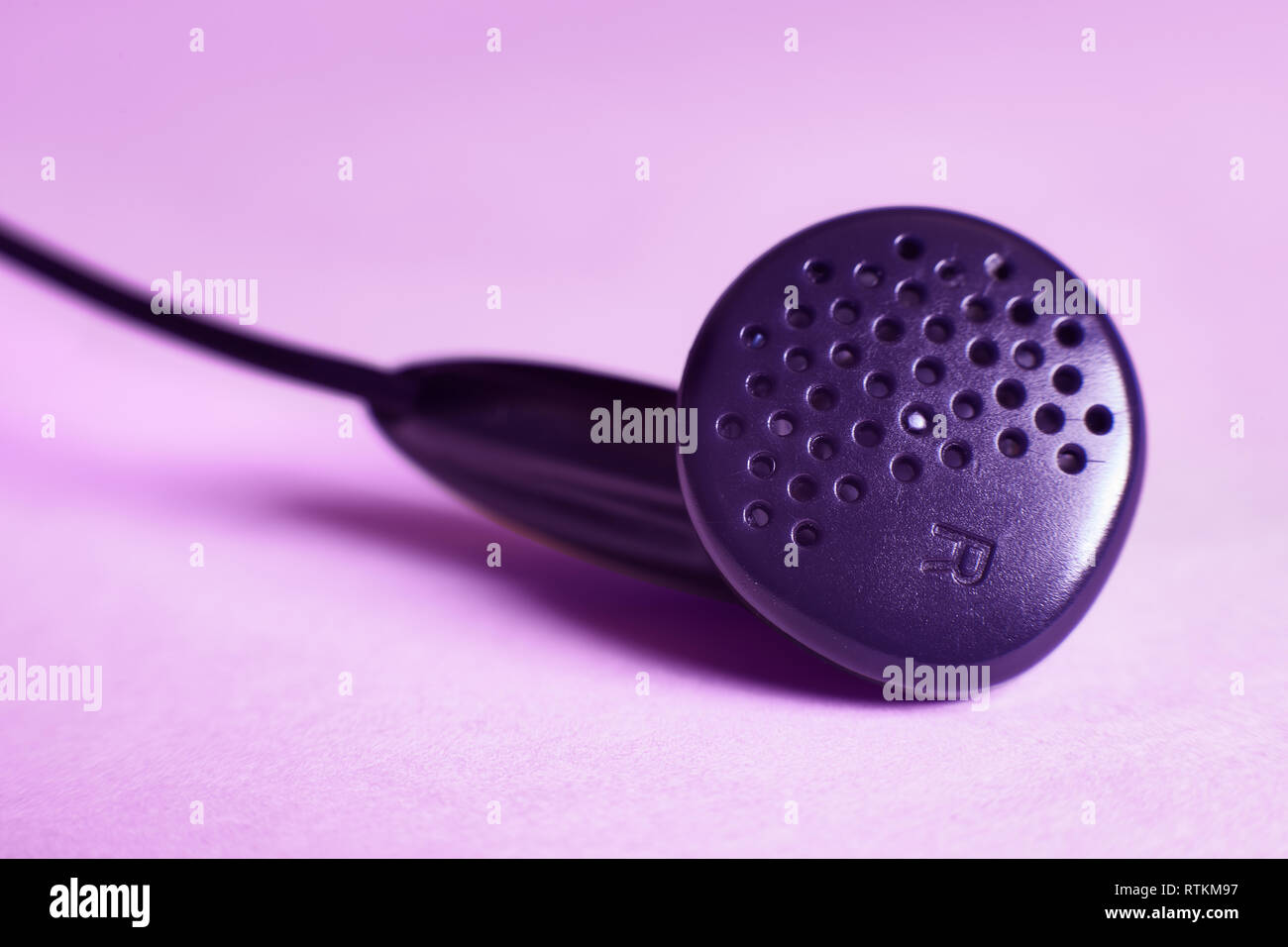 Close-up d'un écouteur droit dans un fond de couleur pourpre Banque D'Images