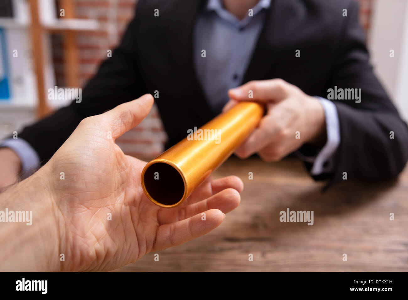 Close-up of a Businessman's Hand passant le relais d'or relais à son Partner Banque D'Images