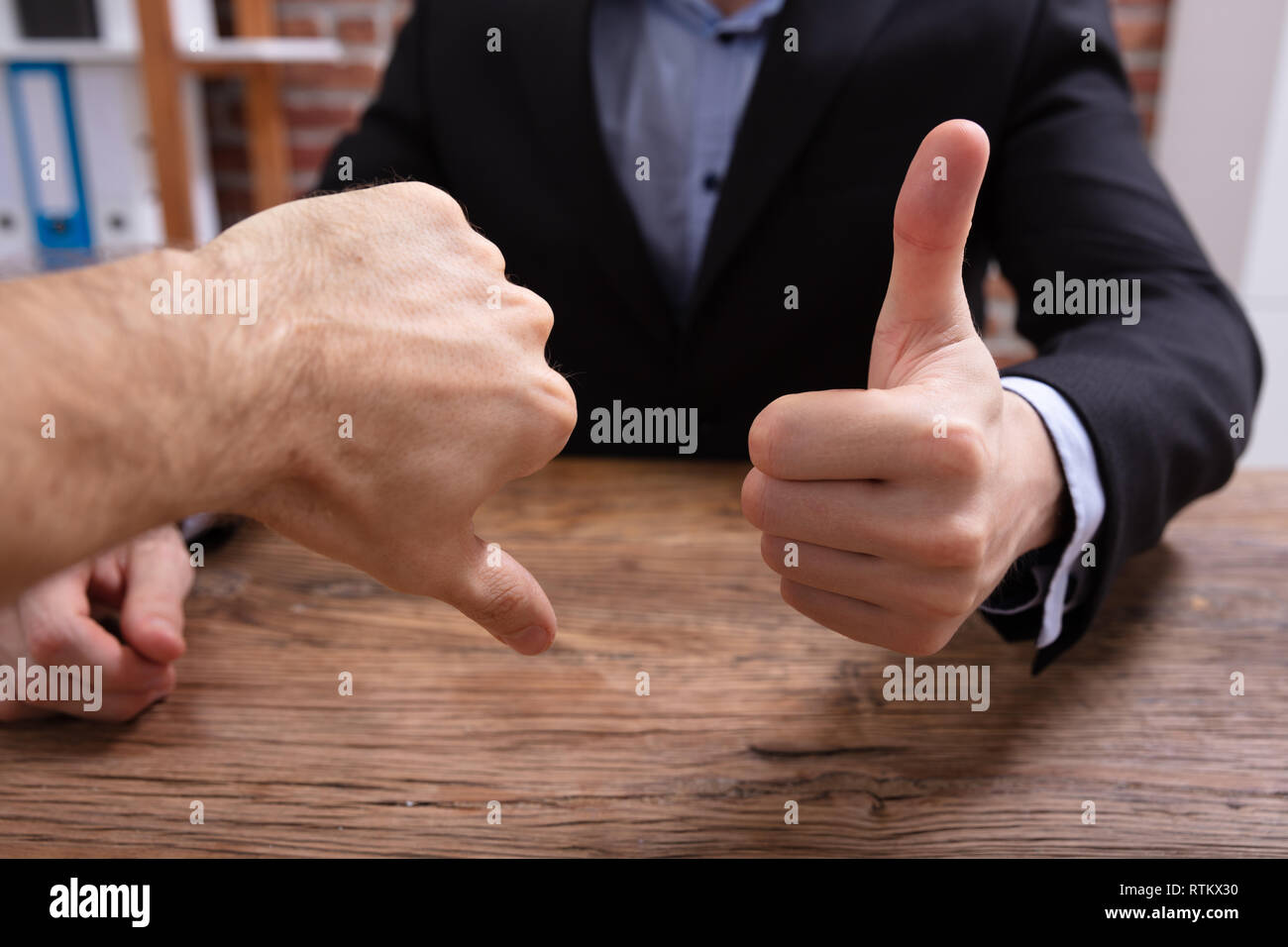 Deux personnes Showing Thumbs Up et signe de pouce vers le bas In Office Banque D'Images