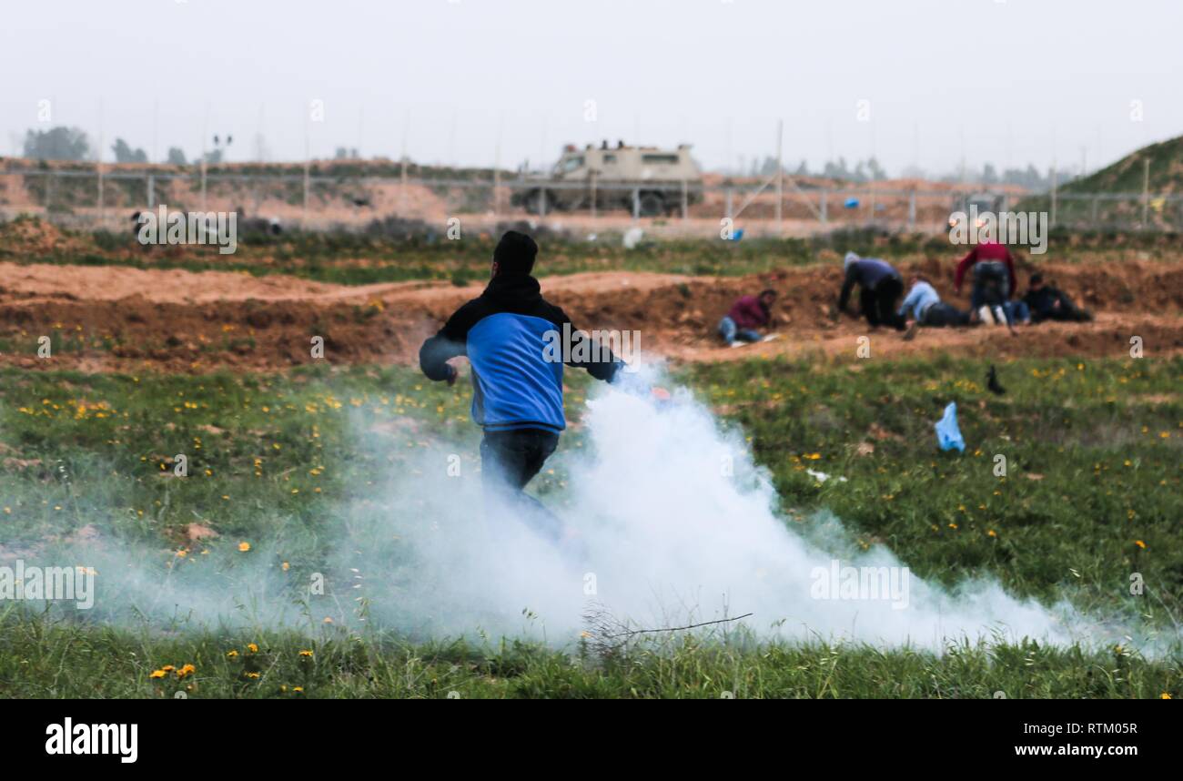Un jeune Palestinien de retour du front une bombe de gaz lacrymogène vers les forces israéliennes au cours d'une "grande marche du retour sur la manifestation de l'est de la frontière israélienne, Khan Yunis dans la bande de Gaza. Banque D'Images