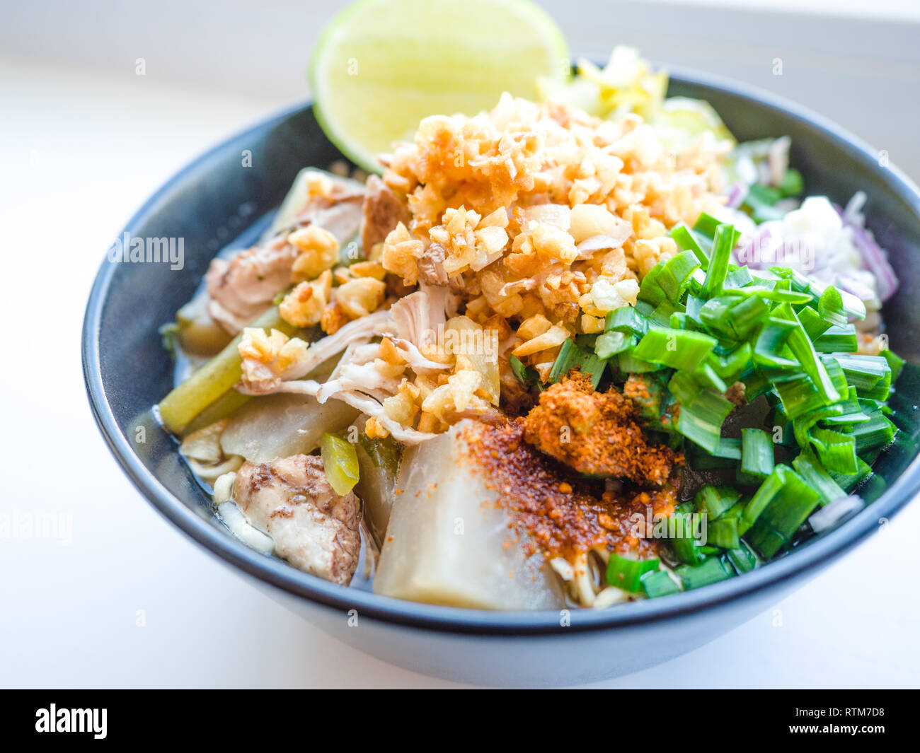 Déchiquetez les nouilles instantanées poulet frit avec de l'ail. le chili en poudre, citron, oignon de printemps et de la soupe avec les épices dans un bol sur le tableau blanc Banque D'Images