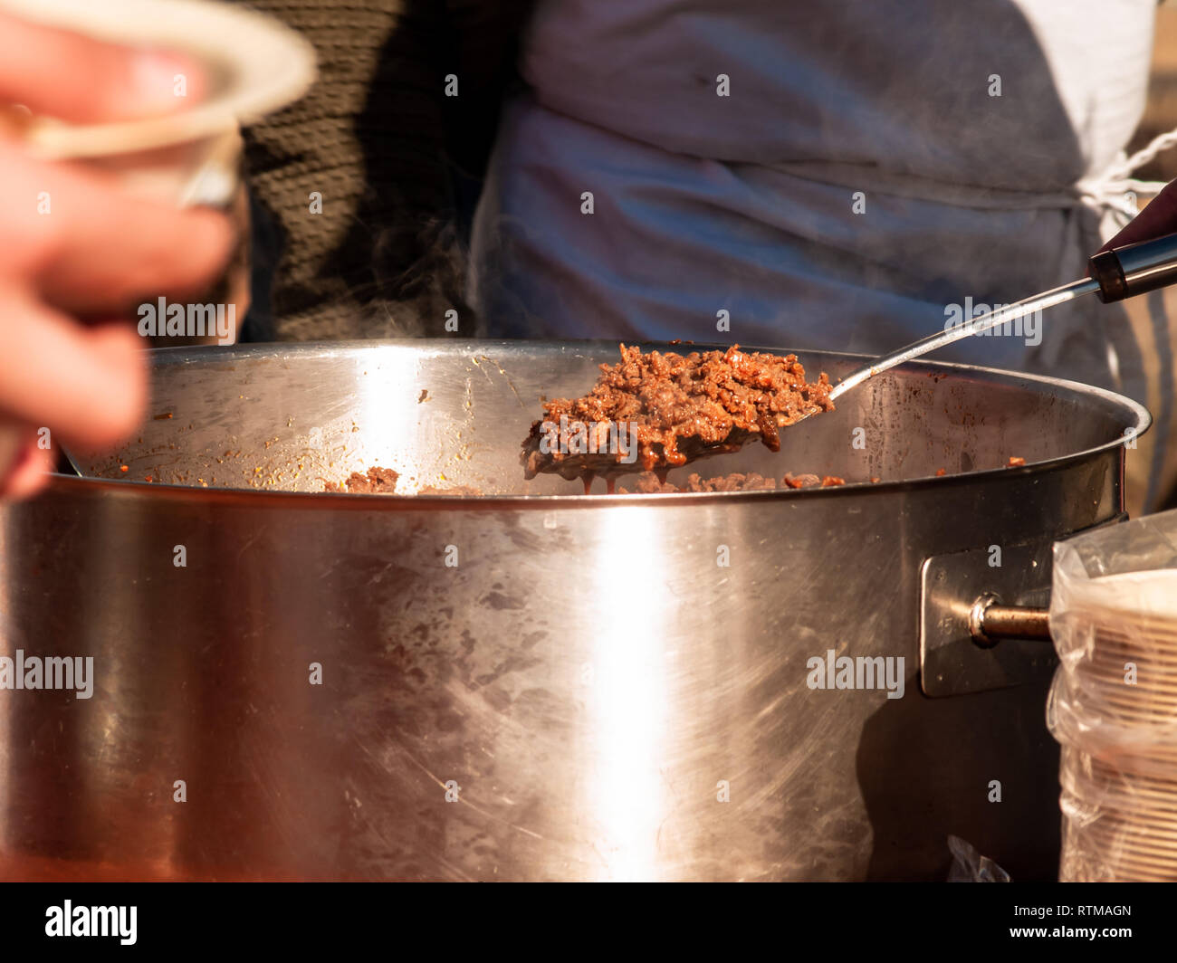 Personne méconnaissable desservant espagnole traditionnelle appelée chichas sur une assiette en carton dans la rue à une fête populaire dans un village de l'Espagne Banque D'Images