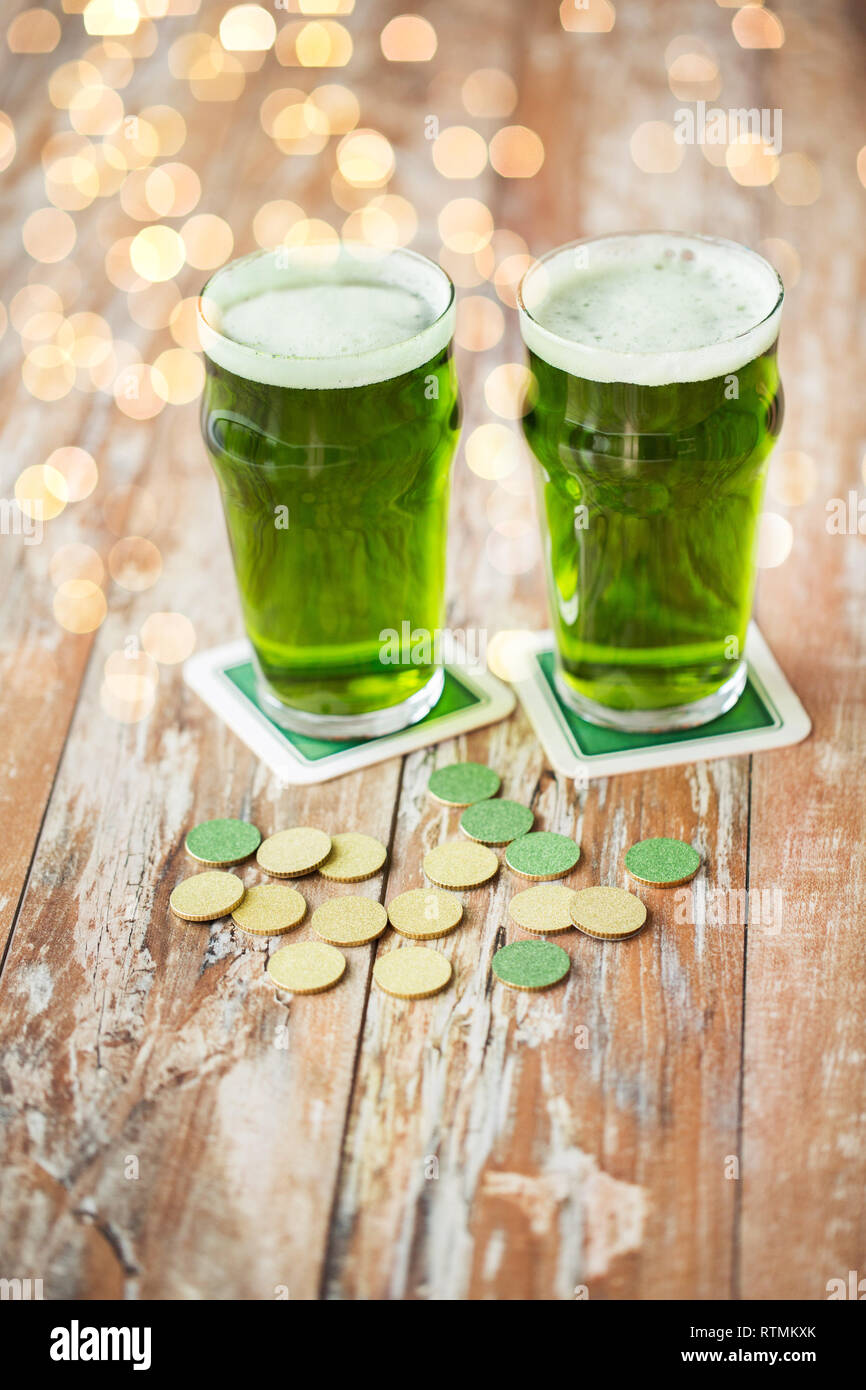 Verres de bière verte et de pièces d'or sur la table Banque D'Images