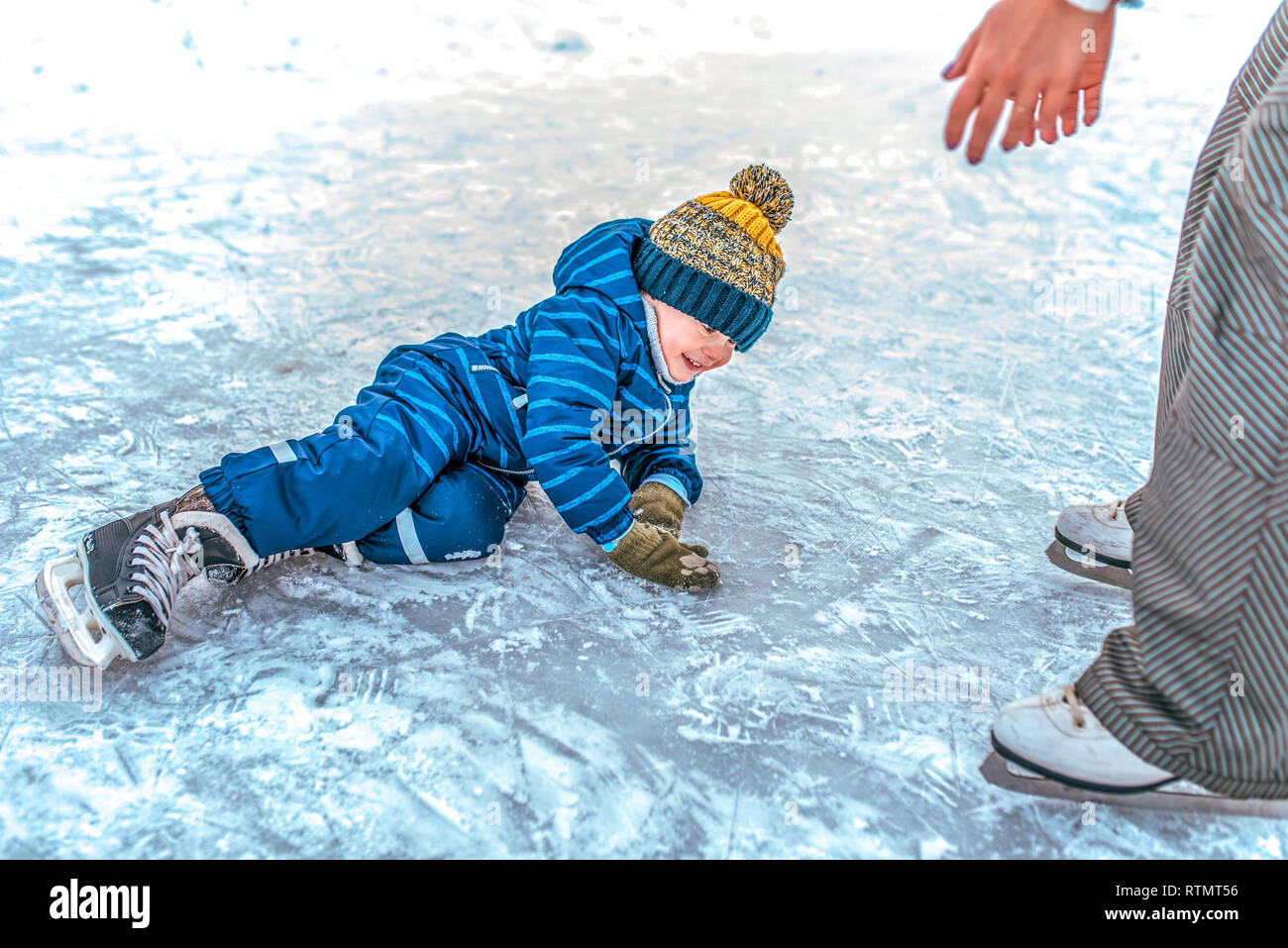 Un petit garçon 2-5 ans, est tombée sur la glace en hiver le patinage sur  glace. Maman soulève son fils. Sourires heureux. Le premier soutien de  patinage de l'apprentissage de l'automne Photo