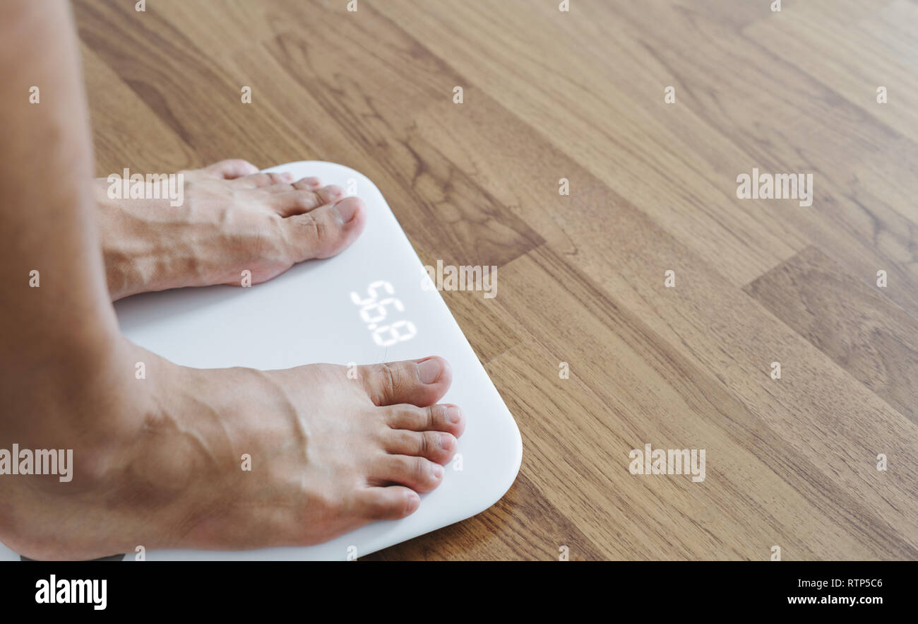 Close up un homme pieds sur la taille d'organisme de contrôle du poids, suivre un régime et perdre du poids concept Banque D'Images