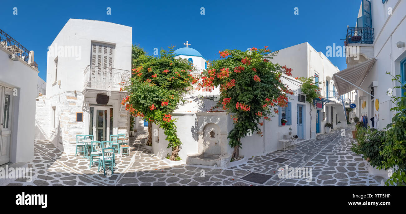 Panorama de la belle rue étroite en Grèce avec un agréable café en plein air et de l'église grecque traditionnelle dans la ville de Parikia sur l'île de Paros, Cyclades Banque D'Images