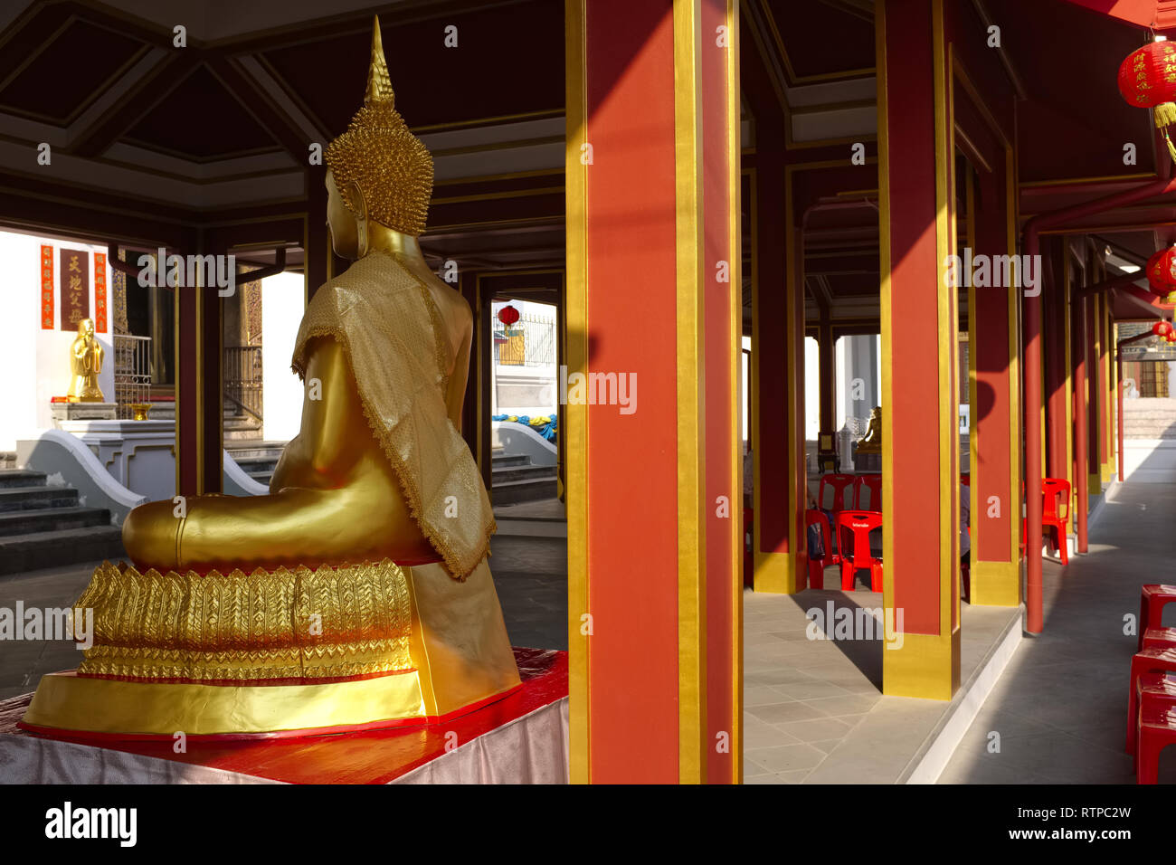 Un Bouddha assis statue et rouge-jaune piliers dans les motifs de Wat Kalayanamit, Thonburi, Bangkok, Thaïlande Banque D'Images