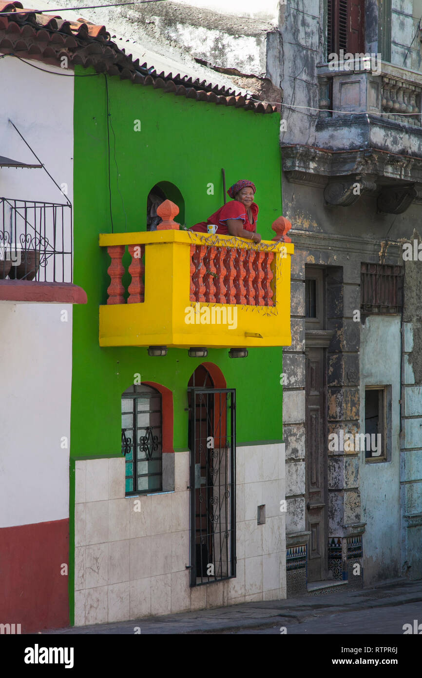 La Havane, Cuba - 21 janvier 2013 : une vue sur les rues de la ville avec des cubains. Un afro-cubain, chubby femme est assise sur le balcon et regarde Ont. Banque D'Images