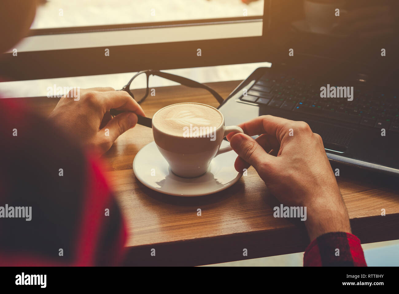 Jeune travailleur indépendant bénéficie d''un café dans un café à l'aide d'un ordinateur portable. Pause café. Travailleur indépendant boit du café par fenêtre Banque D'Images