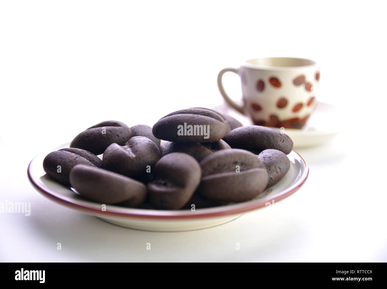 Les grains de café au chocolat dans une tasse sur une soucoupe, fond blanc. Banque D'Images