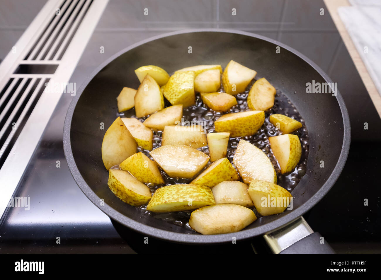 Frire les pois et le vinaigre balsamique dans une casserole sur une cuisinière. Banque D'Images