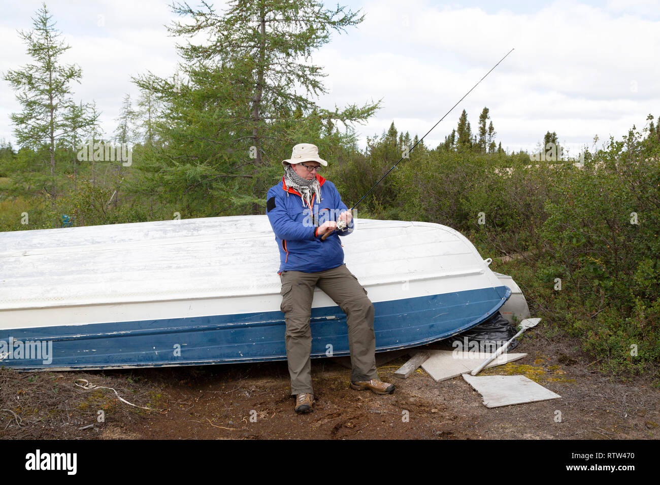 Un pêcheur par un bateau de pêche dans le nord du Manitoba, Canada. Lodges fonctionner fly in fly out (FIFO), la pêche. Banque D'Images