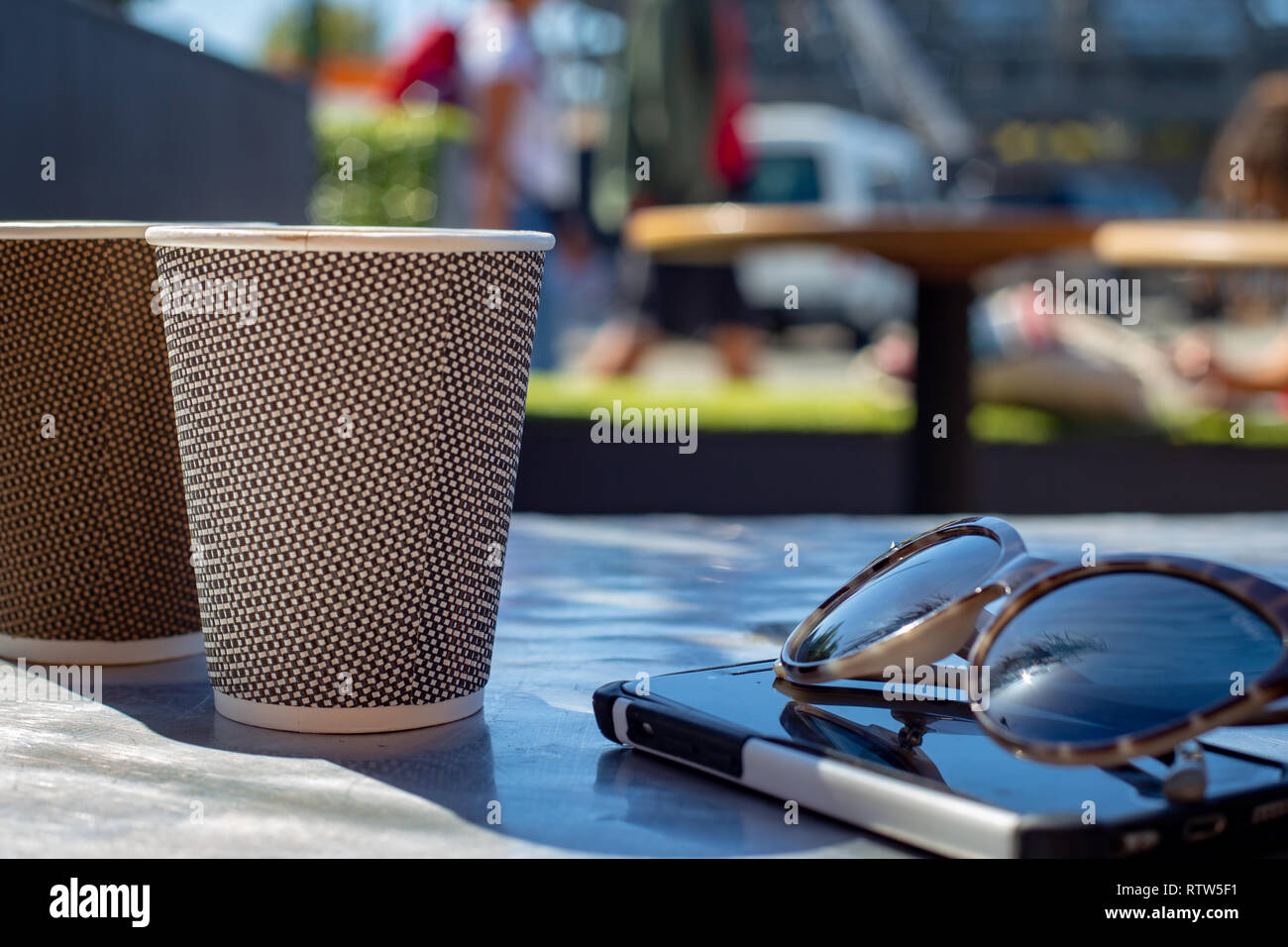 Profiter du café à l'ombre avec cellphone et lunettes assis sur la table Banque D'Images