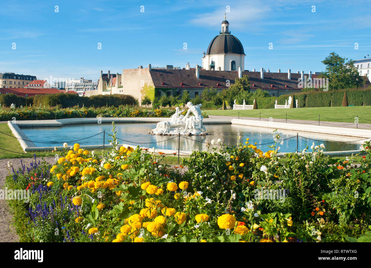 Vue sur un dôme à proximité du palais du Belvédère, parterre de fleurs et plusieurs statues blanches de personnes dans l'eau d'un étang contre un ciel b Banque D'Images