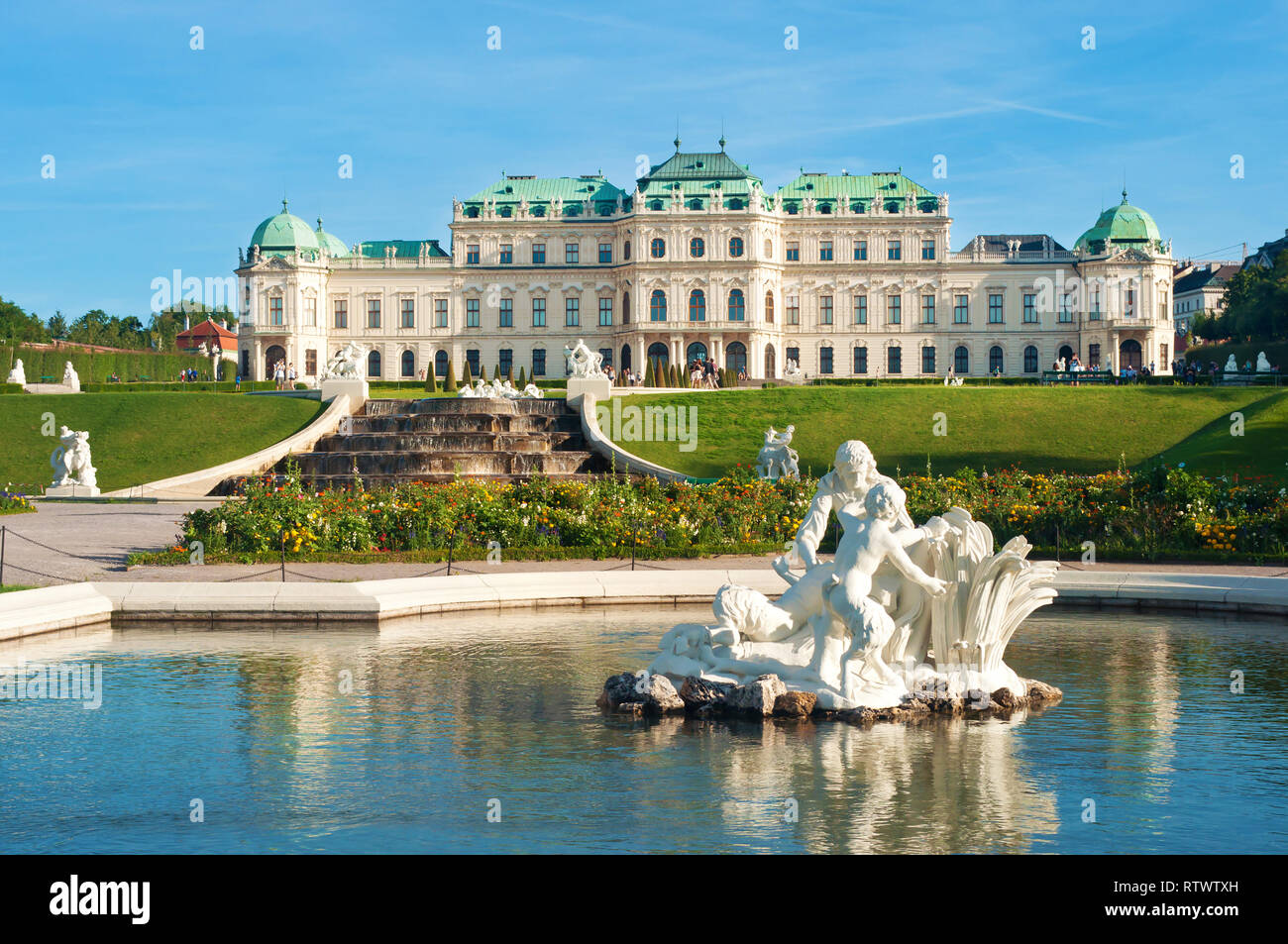 Vue sur le palais du Belvédère, fontaine, parterre de fleurs et plusieurs statues blanches de personnes dans l'eau d'un étang contre un ciel bleu Banque D'Images