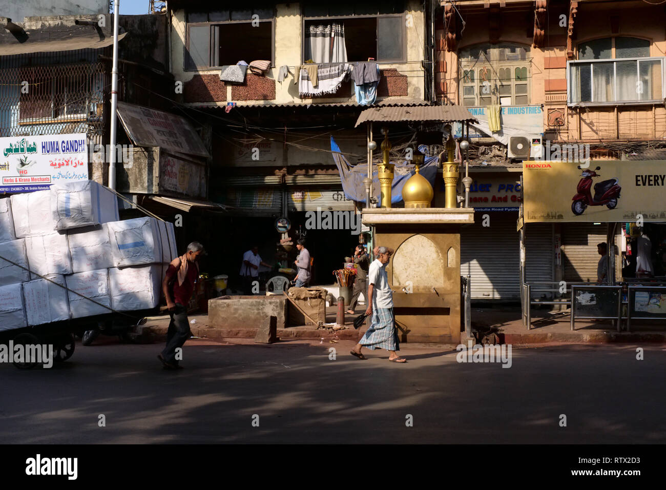 Une scène de rue à Pydhonie salon, Mumbai, Inde, à prédominance musulmane d'une partie de la ville ; avec un extracteur de charrettes et d'une petite mosquée dans la symbolique b/g Banque D'Images