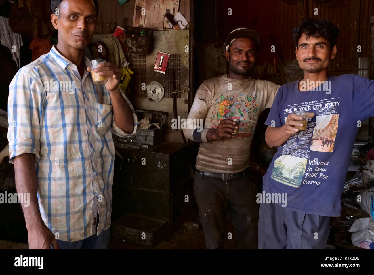 Employés dans un petit atelier et terne à Mumbai, Inde, ayant une pause thé thé masala potable, c.-à-thé au lait et épices Banque D'Images