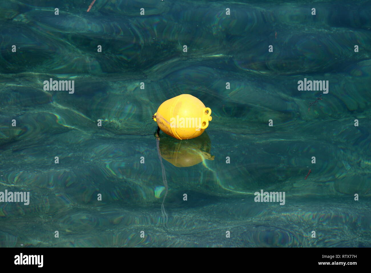 Bouée jaune en plastique flottant sur une mer calme avec des roches  visibles et connecté à la corde attachée bas sur chaude journée ensoleillée  Photo Stock - Alamy