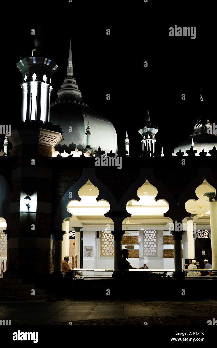 Les hommes la lecture, Masjid Jamek Mosquée Jamek (la nuit), Kuala Lumpur, Malaisie. Banque D'Images