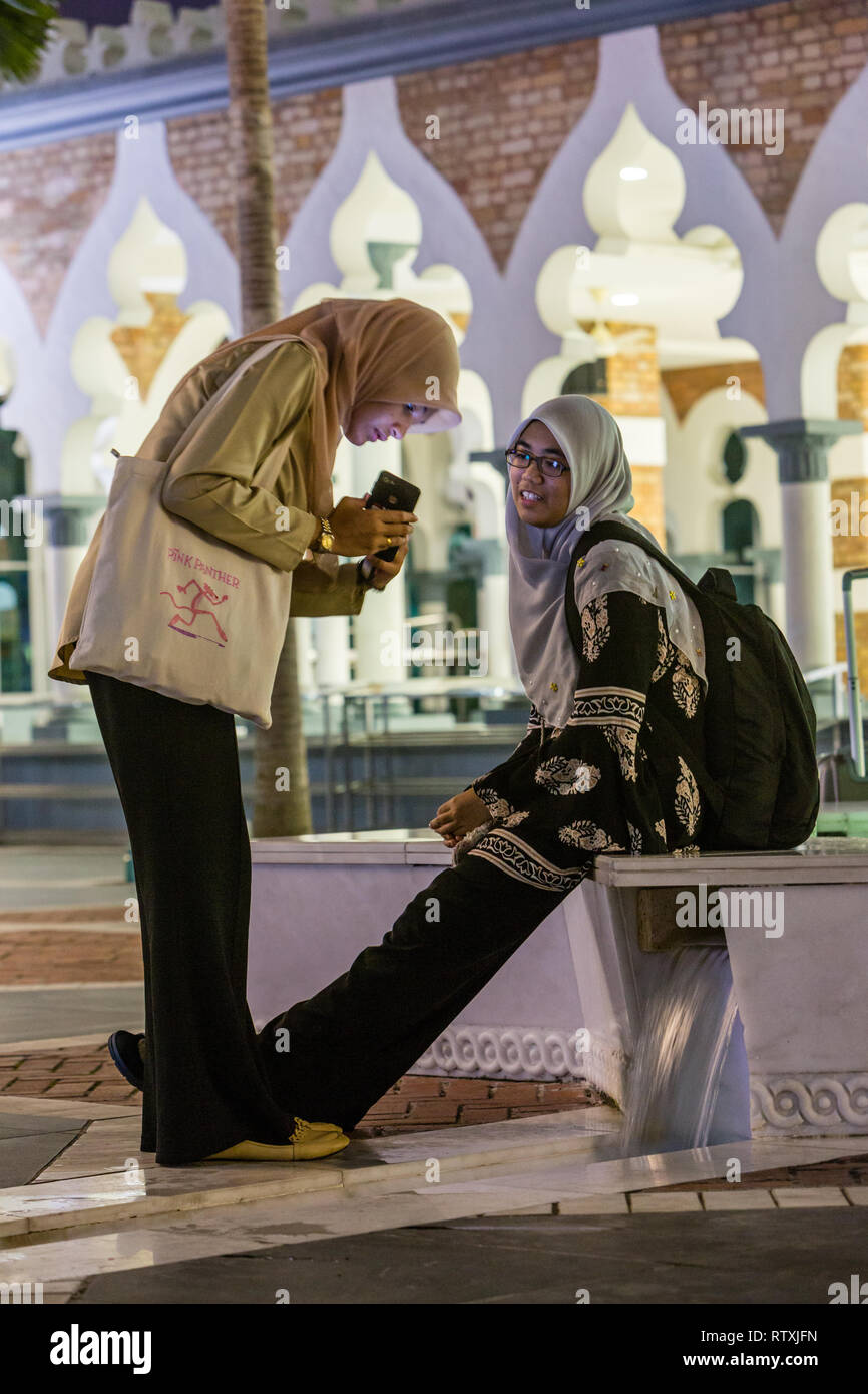 Les femmes à la recherche de téléphone cellulaire, la Mosquée Jamek Masjid Jamek (), Kuala Lumpur, Malaisie. Banque D'Images