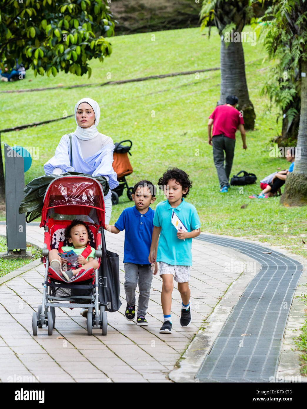 Mère de Malaisie à marcher avec ses enfants, le parc KLCC, Kuala Lumpur, Malaisie. Banque D'Images