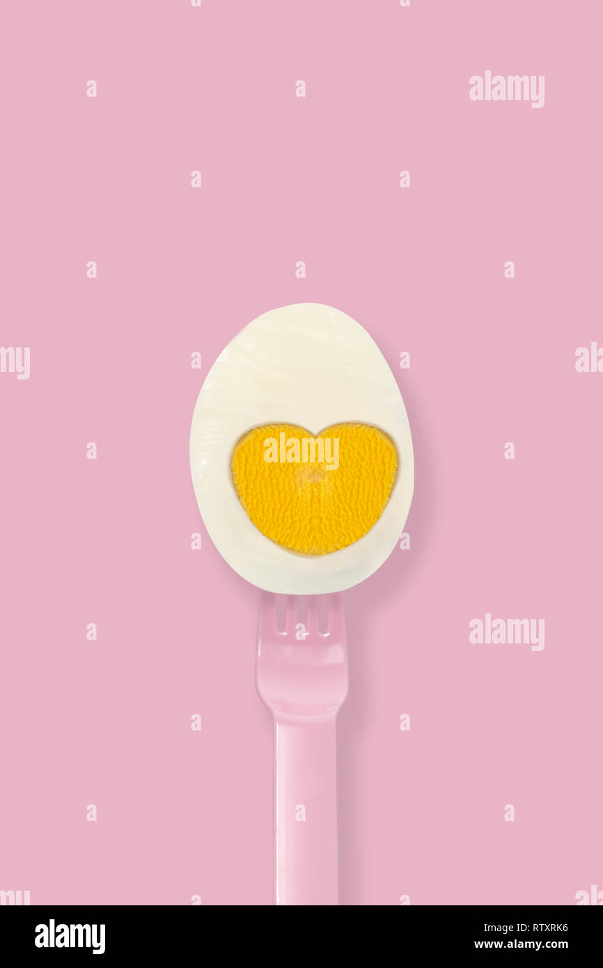 La moitié oeuf dur sur un tablier rose sur fond rose, un minimum d'eater concept. Banque D'Images