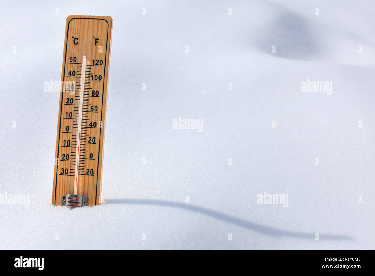 Thermomètre en bois debout dans la neige, soleil, ombre sinueuse coulée  colonne rouge montrant 0 degrés Celsius la température. Hiver / neige  prochains concept Photo Stock - Alamy