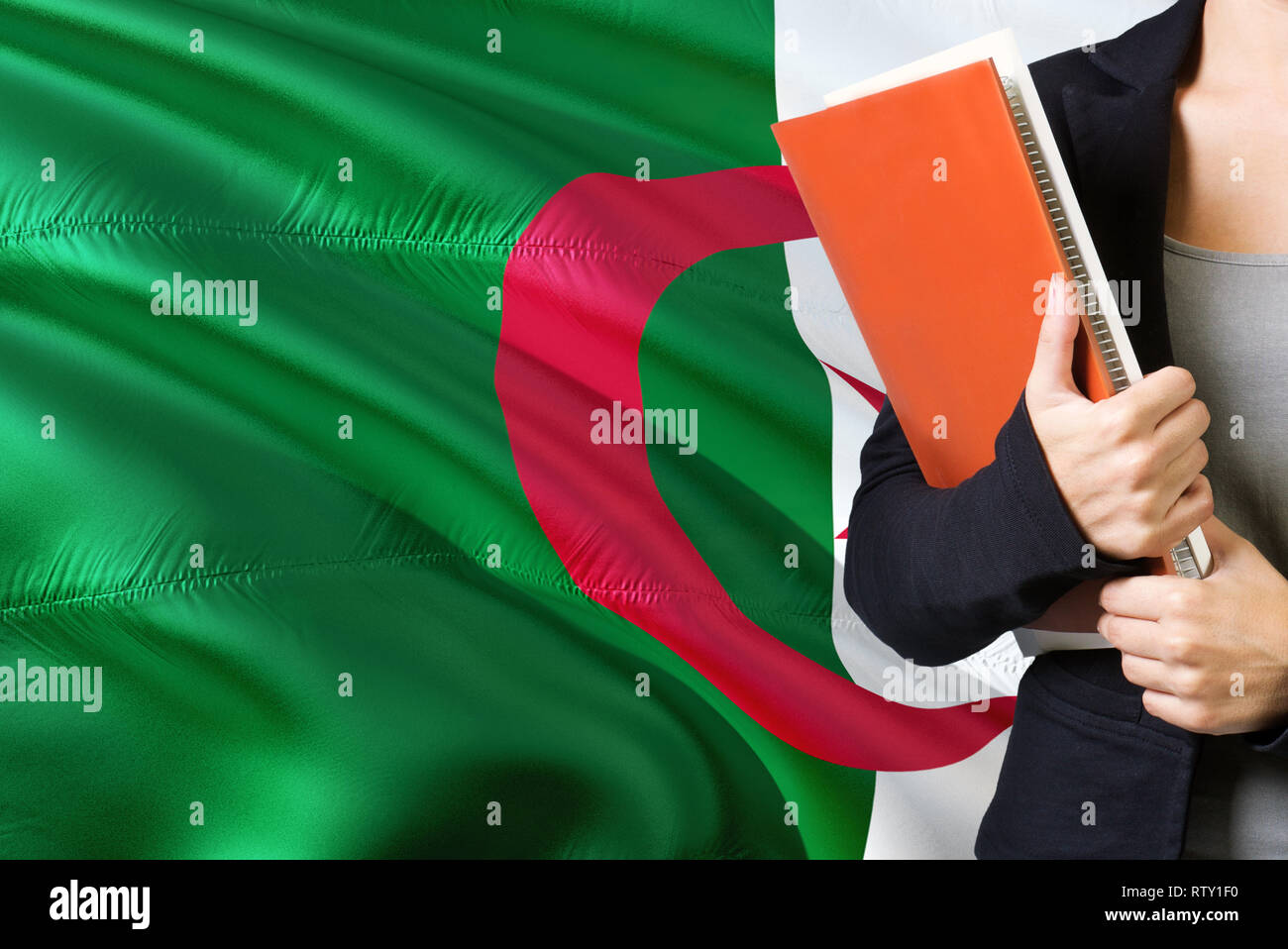 Concept d'apprentissage de la langue algérienne. Jeune femme debout avec le  drapeau de l'Algérie dans l'arrière-plan. Teacher holding books, couverture  de livre blanc orange Photo Stock - Alamy