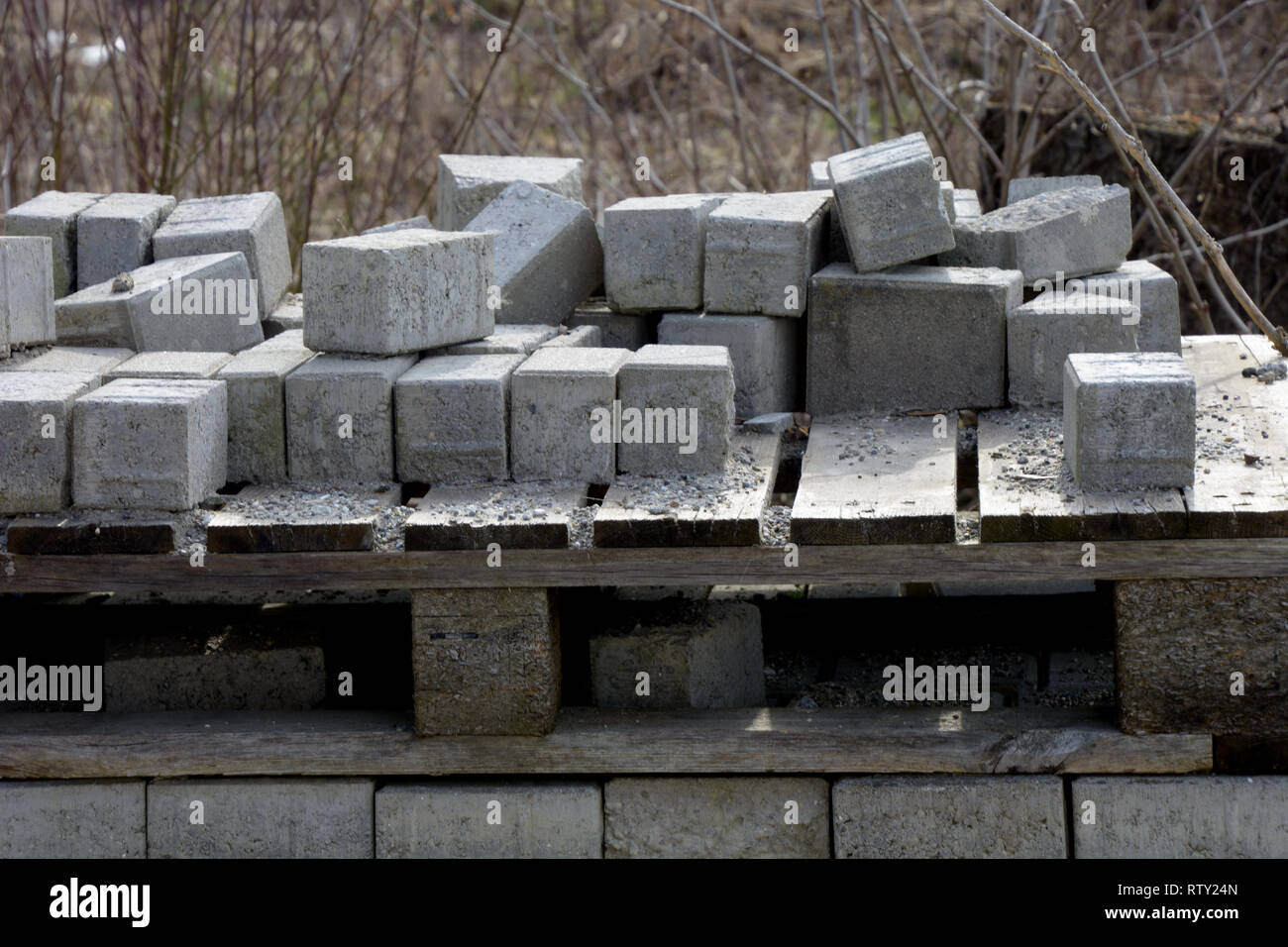 Pile des blocs de ciment gris utilisé pour le pavage des trottoirs, des blocs de béton empilés sur une palette de bois pourri dans la construction site Banque D'Images