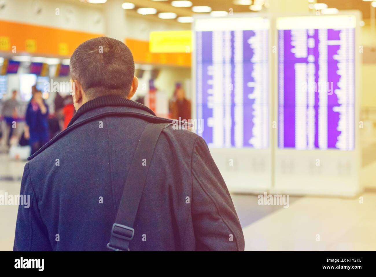 L'homme avec un sac à l'aéroport près de horaire de vol Banque D'Images
