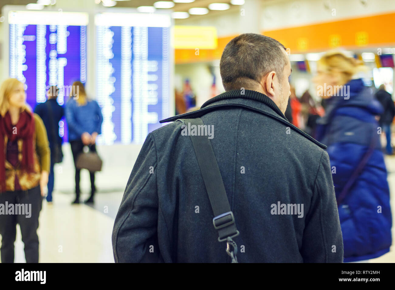 L'homme avec un sac à l'aéroport à l'arrière-plan d'un panneau d'affichage Banque D'Images