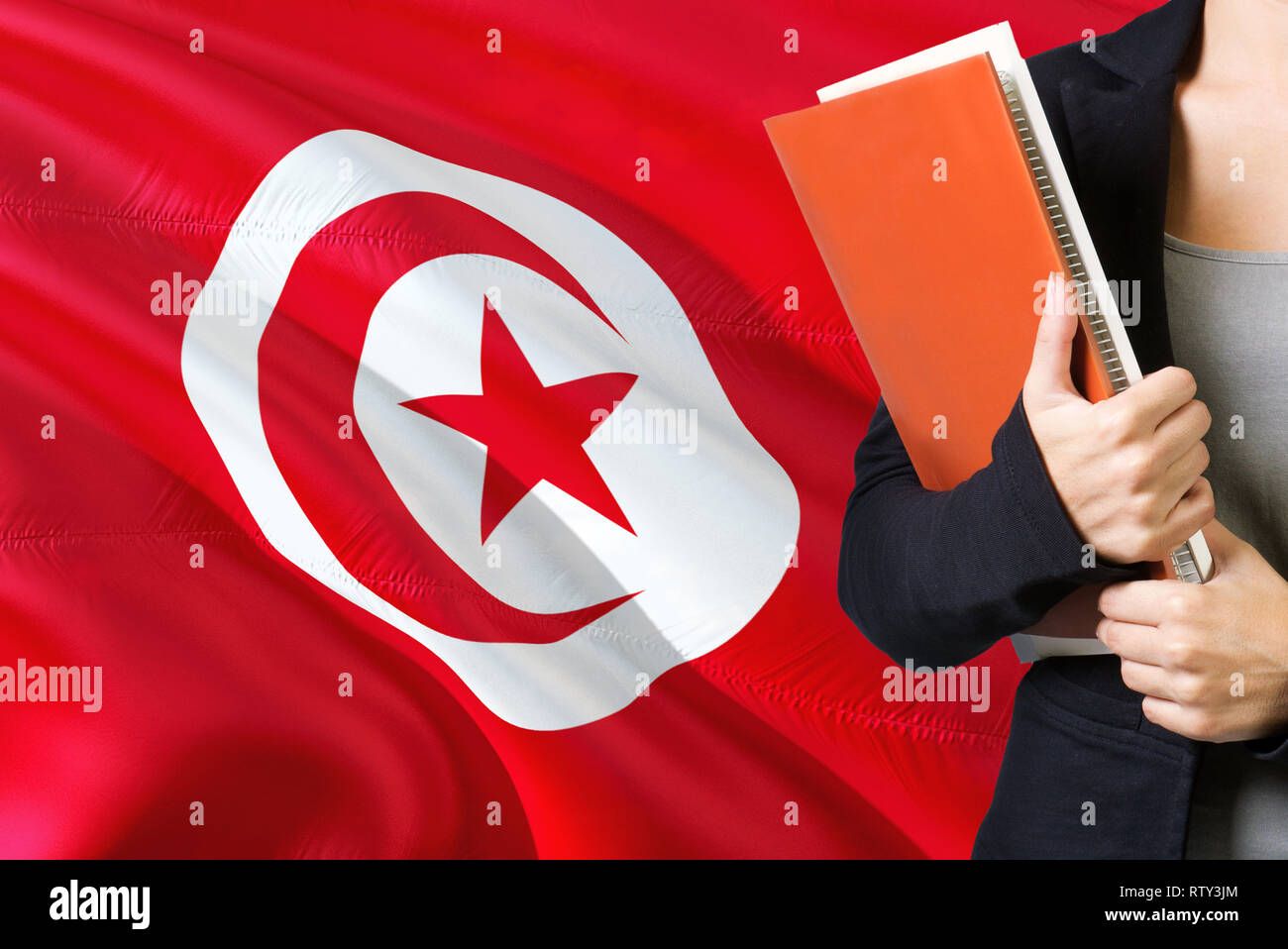Concept d'apprentissage de la langue tunisienne. Jeune femme debout avec le  drapeau de la Tunisie dans l'arrière-plan. Teacher holding books, couverture  de livre blanc orange Photo Stock - Alamy