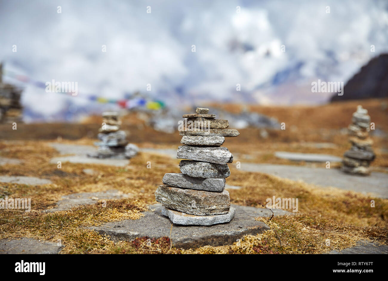 Tas de pierres et de drapeaux de prière Tibetains Lung Ta au camp de base à l'Himal Mardi Nuageux sommets de montagnes de l'Himalaya au Népal Banque D'Images