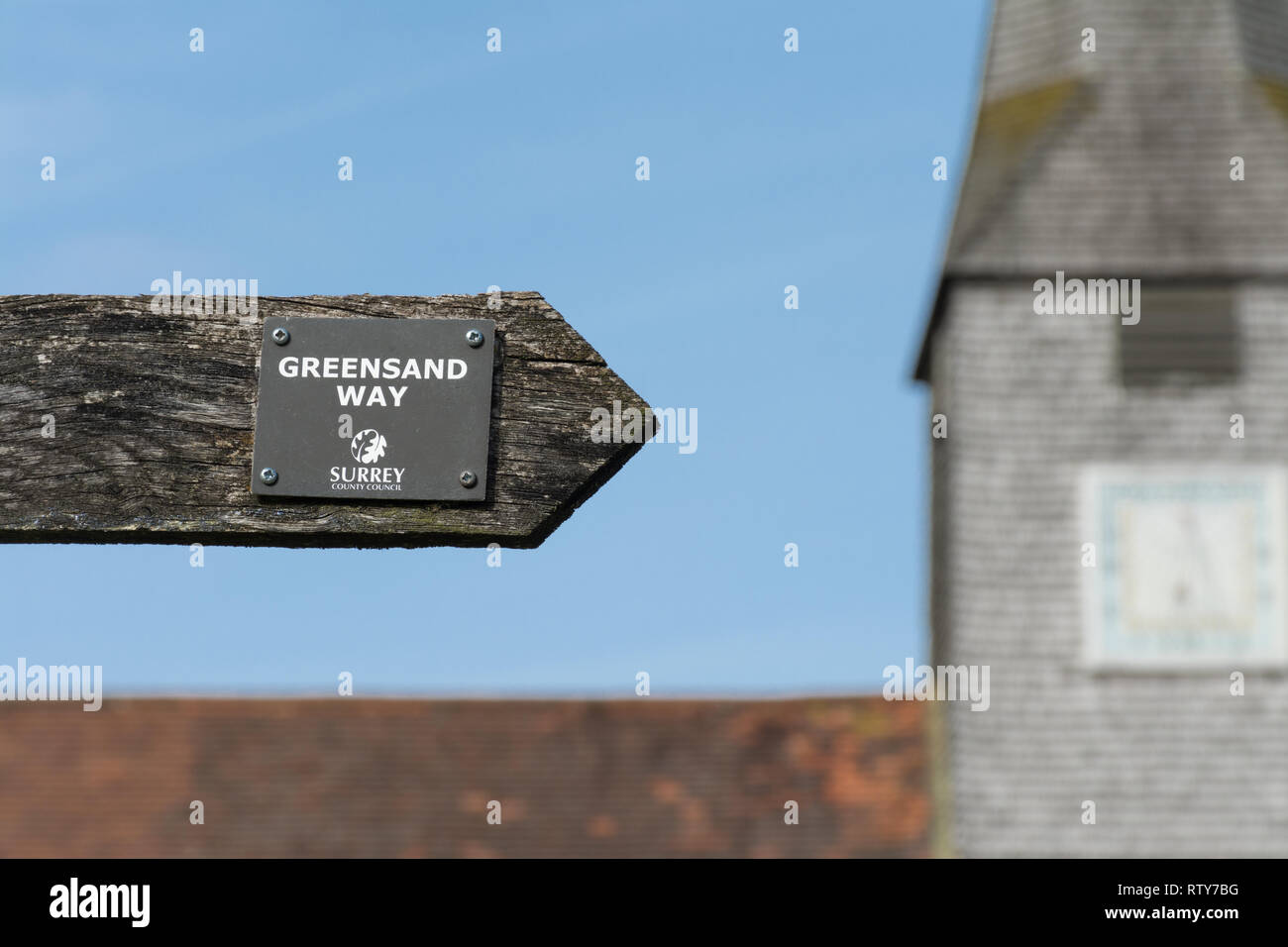 Panneau routier (fingerpost) vers la direction de la manière de sables verts chemin longue distance avec une église en arrière-plan, Surrey, UK Banque D'Images