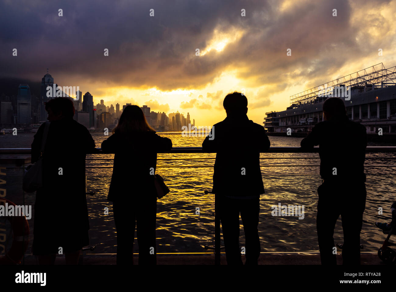 Silhouettes de touristes affichage magnifique coucher de soleil sur le port de Victoria et les toits de Hong Kong, Chine Banque D'Images