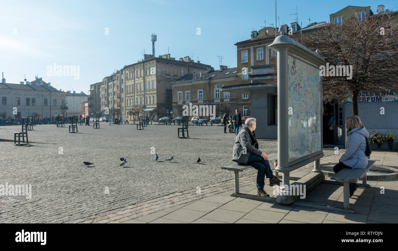 Les gens l'étude d'une carte à l'chaises métalliques à la mémoire des juifs tués sur la Place des Héros du Ghetto, Cracovie, Pologne Banque D'Images