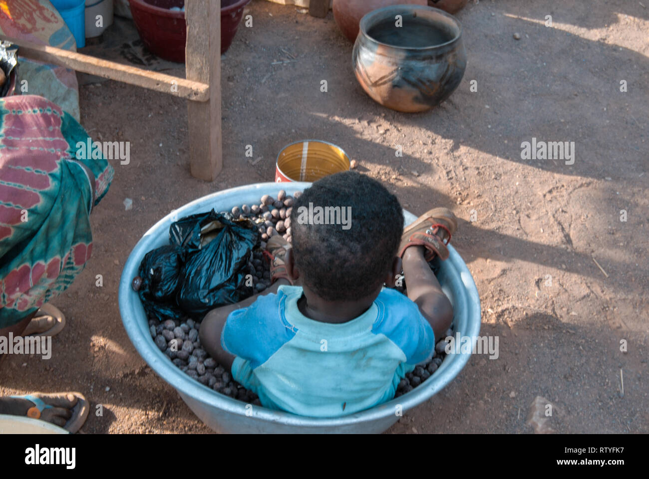 Une belle photo d'un garçon dans un bol plein de shea haricots. Les grains sont utilisés pour produire du beurre de karité. Banque D'Images