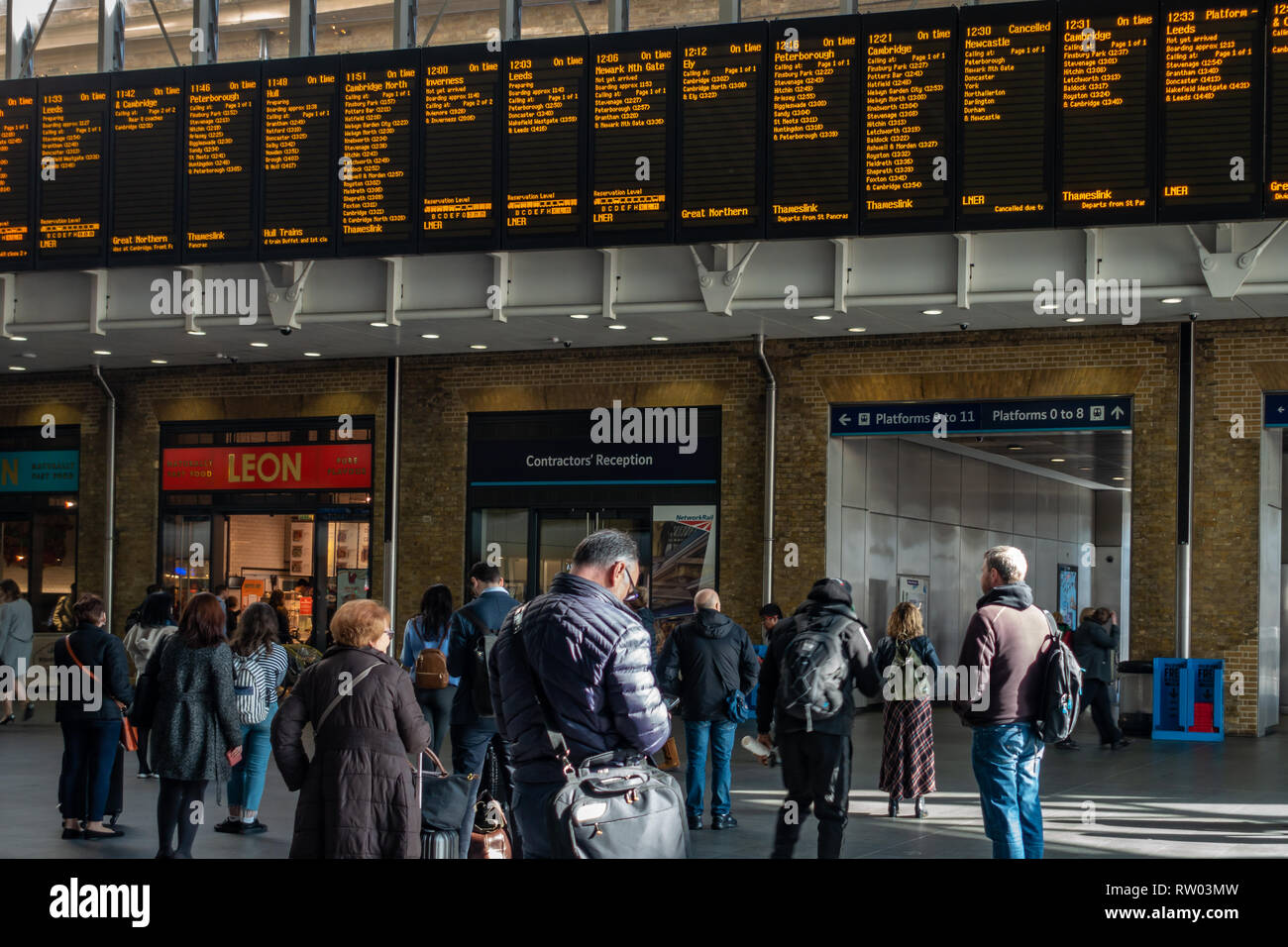 Les passagers des trains à la recherche au départ du train de l'information électronique Inscrivez-vous à la gare de Kings Cross, Londres, Angleterre Banque D'Images