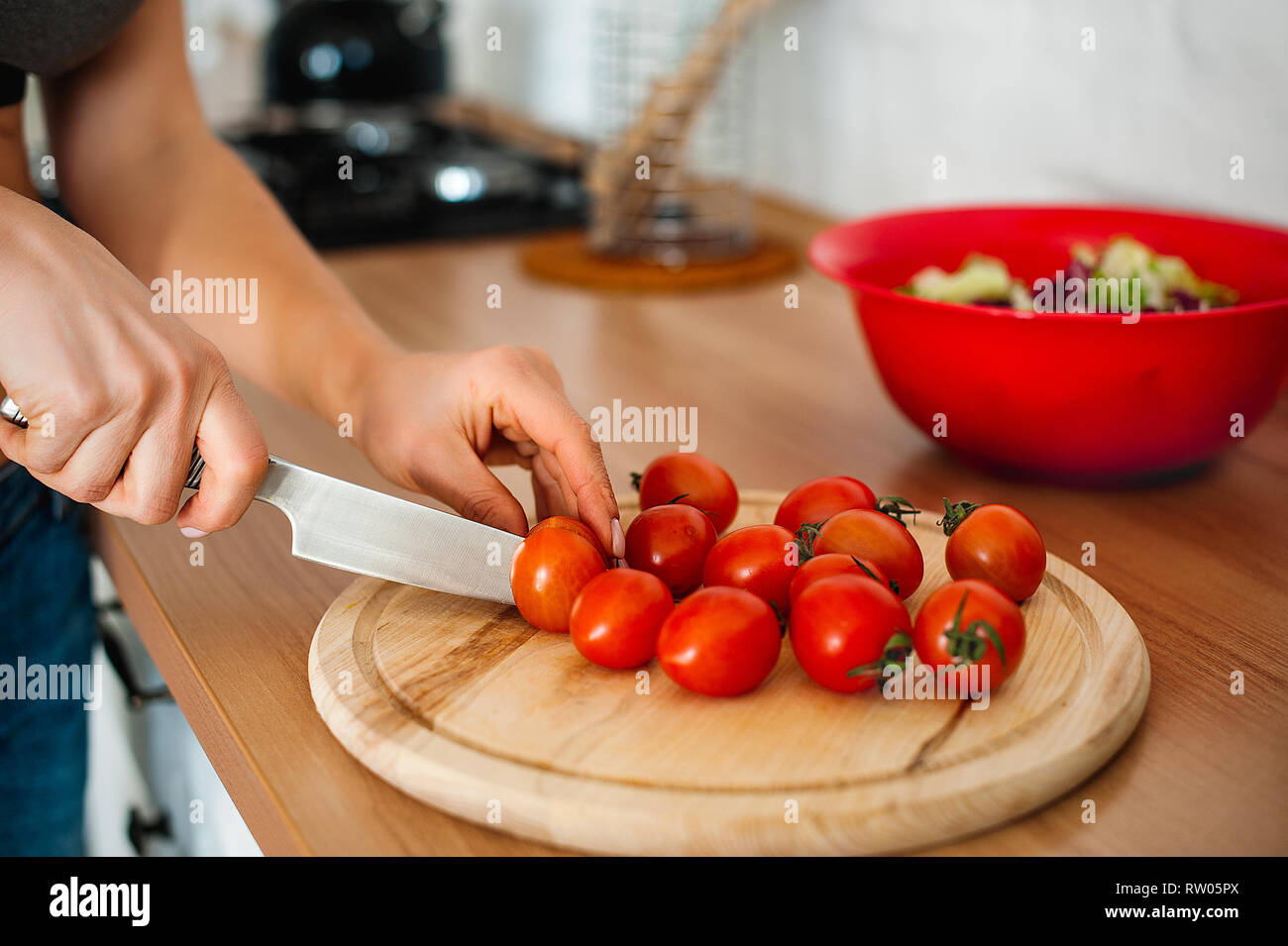La cuisine et accueil concept - close up main de femme de tomate de coupe sur une planche à découper avec couteau Banque D'Images