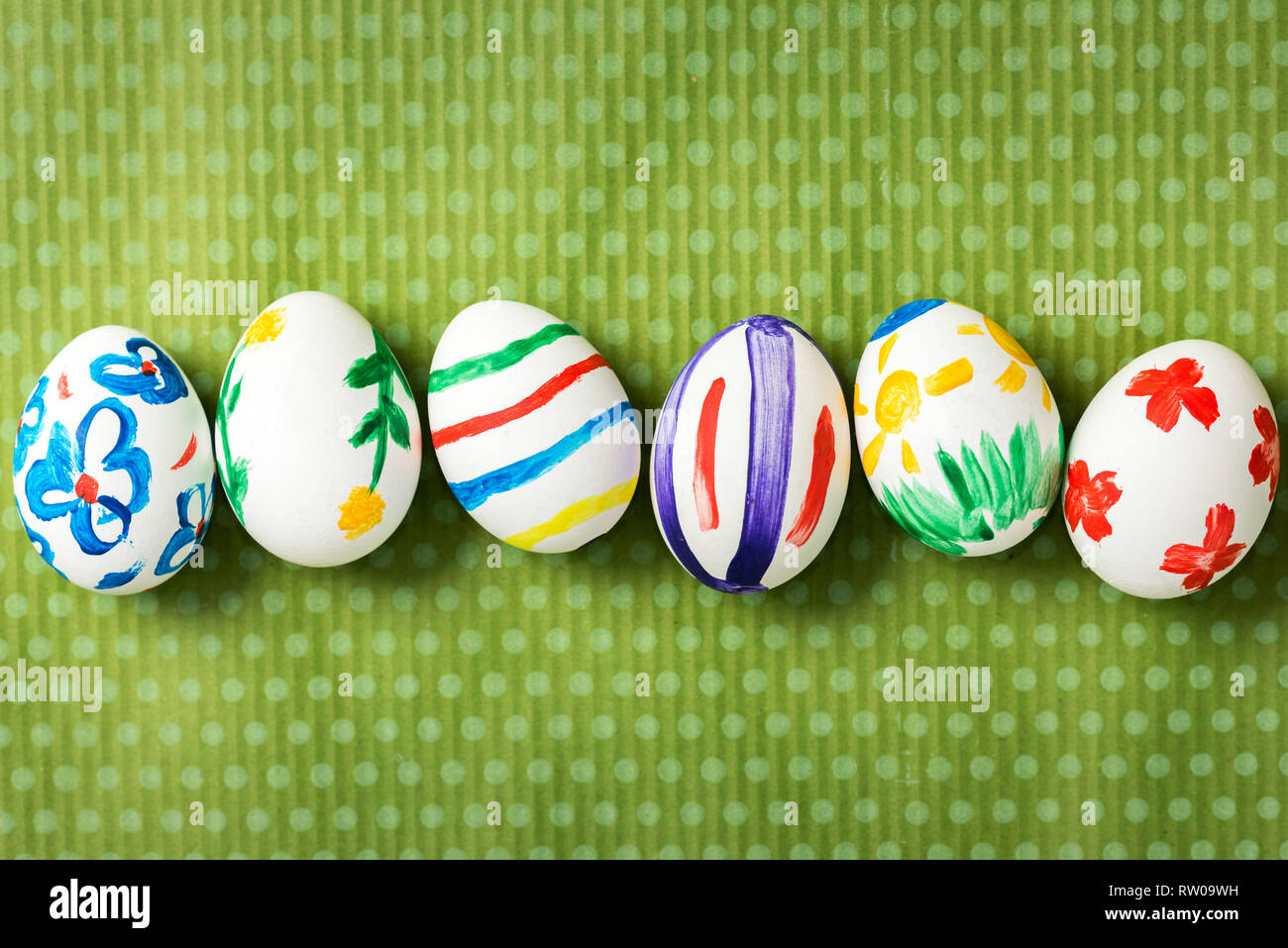 Les oeufs de Pâques peints à la main sur un beau fond vert à pois blancs. Arrière-plan de fête. Idées de Pâques. L'espace pour le texte. Joyeuses Pâques. Banque D'Images