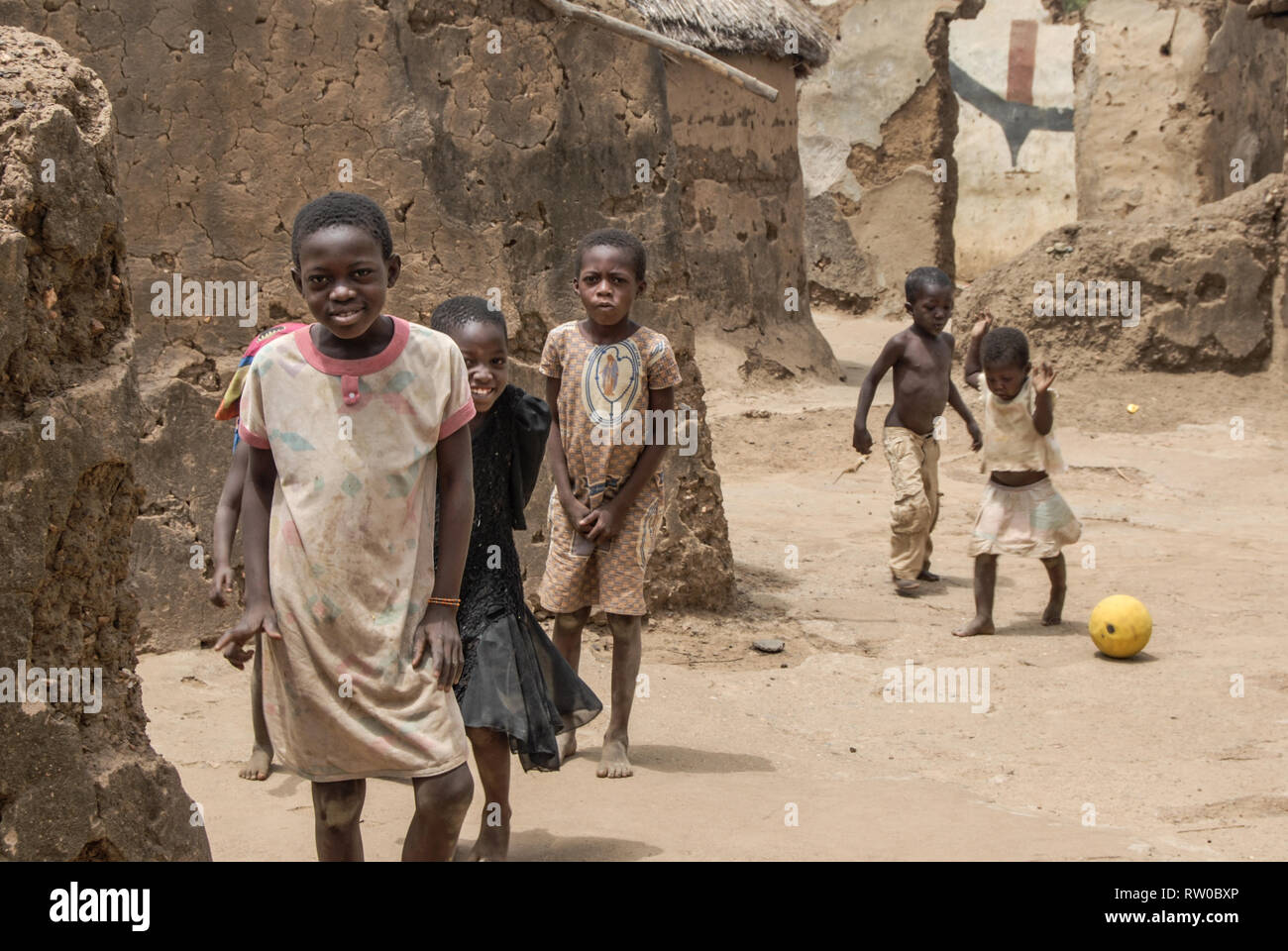 Une esthétique photo de belle heureux des enfants ghanéens posant pour une photo en jouant au football sur une rue sale et poussiéreux. Banque D'Images