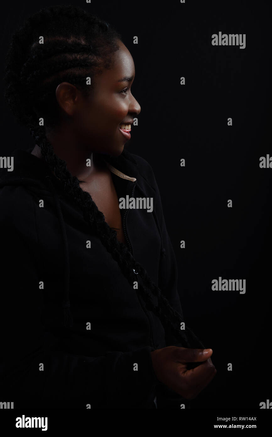 Femme naturelle avec la peau foncée de rire et vêtu de noir hoodie Banque D'Images
