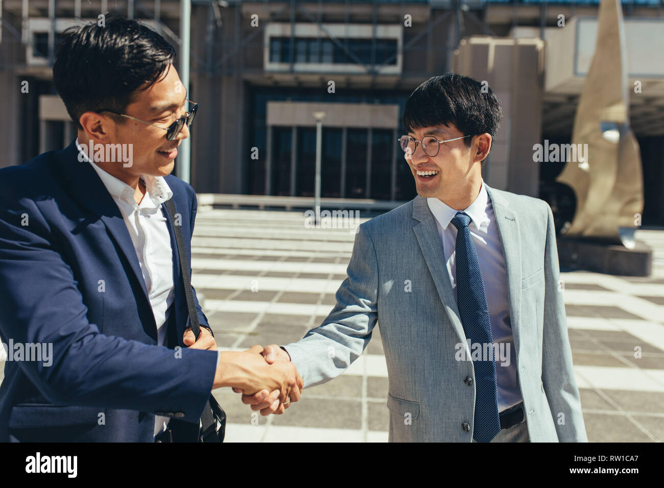 Deux hommes d'affaires se serrer la main à l'extérieur. Asian businesspeople agiter la main à l'extérieur. Banque D'Images