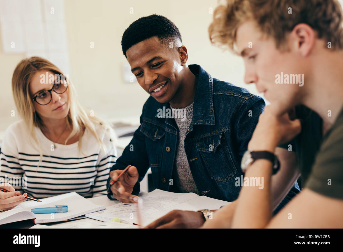 African boy étudier avec ses camarades. Groupe de travail multi-ethnique sur les affectations des élèves du collège dans le campus. Banque D'Images