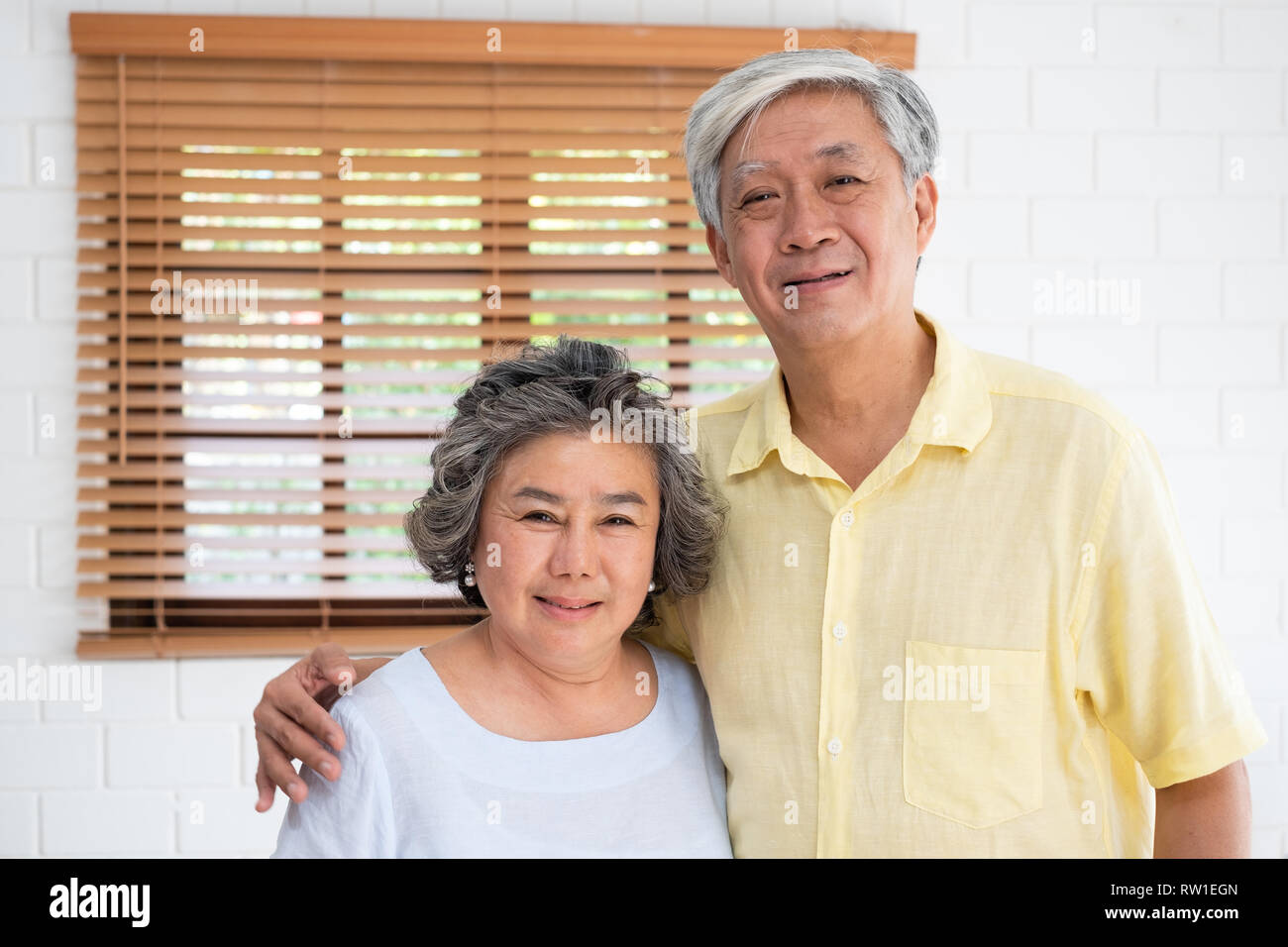 Asian senior couple embrasser togerther et looking at camera dans la salle de séjour à la maison.Bonne retraite lfie.aging de home concept Banque D'Images