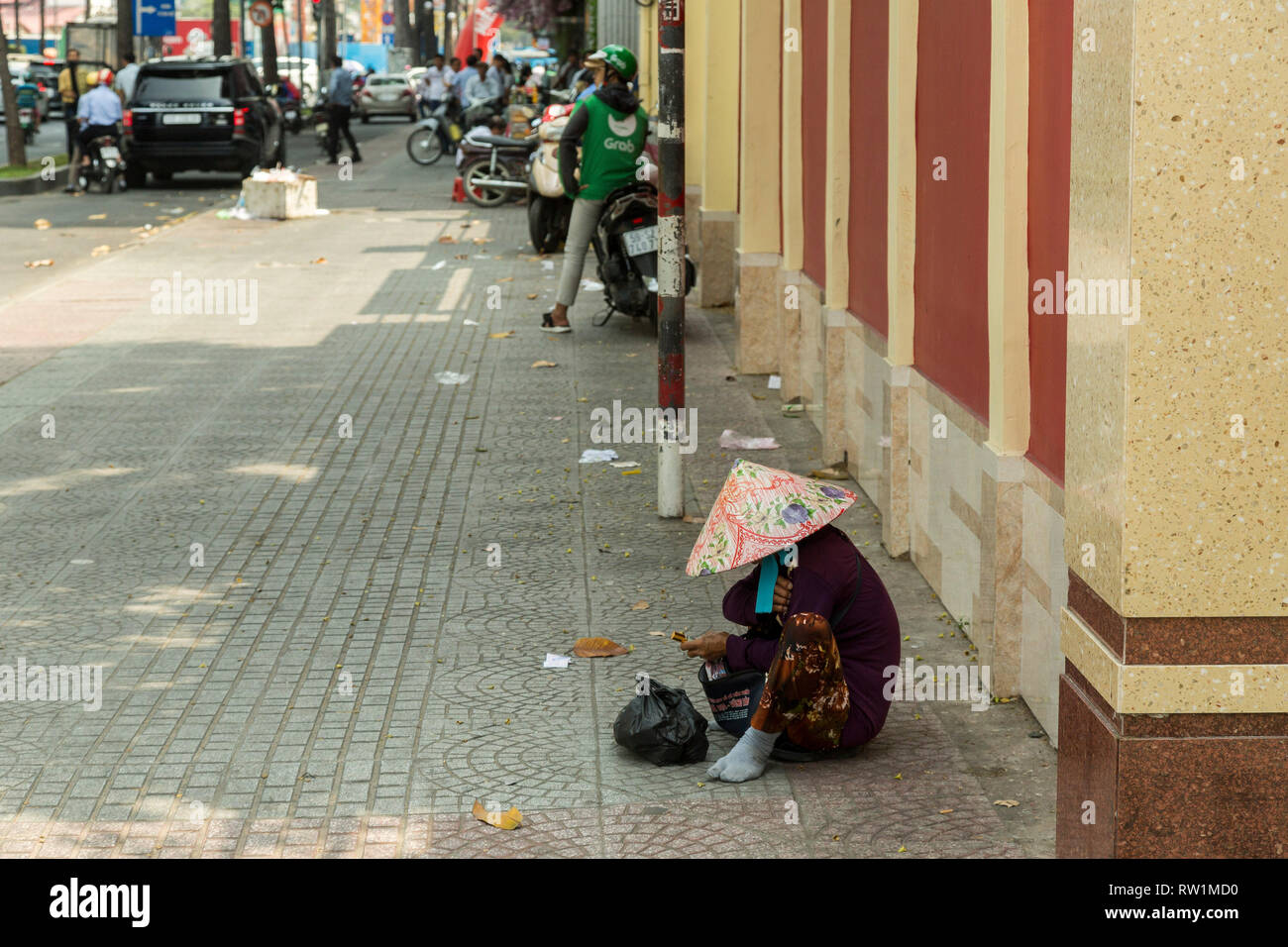 Femme assise dans la rue à Ho Chi Minh, Vietnam Banque D'Images