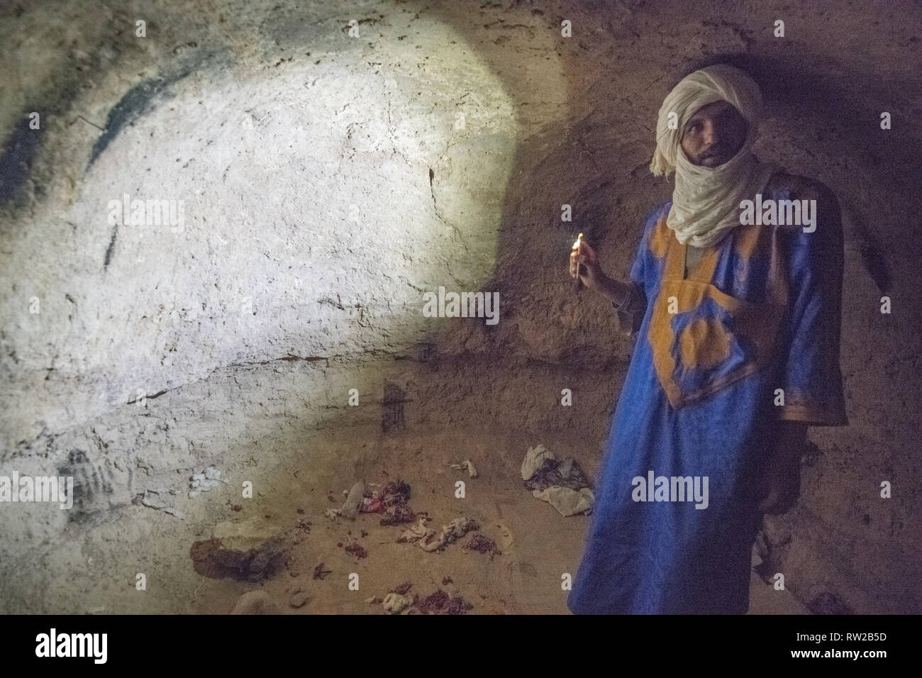 L'homme Téléphone clignotant lumière contre mur Grotte, Foum Zguid, Maroc Banque D'Images