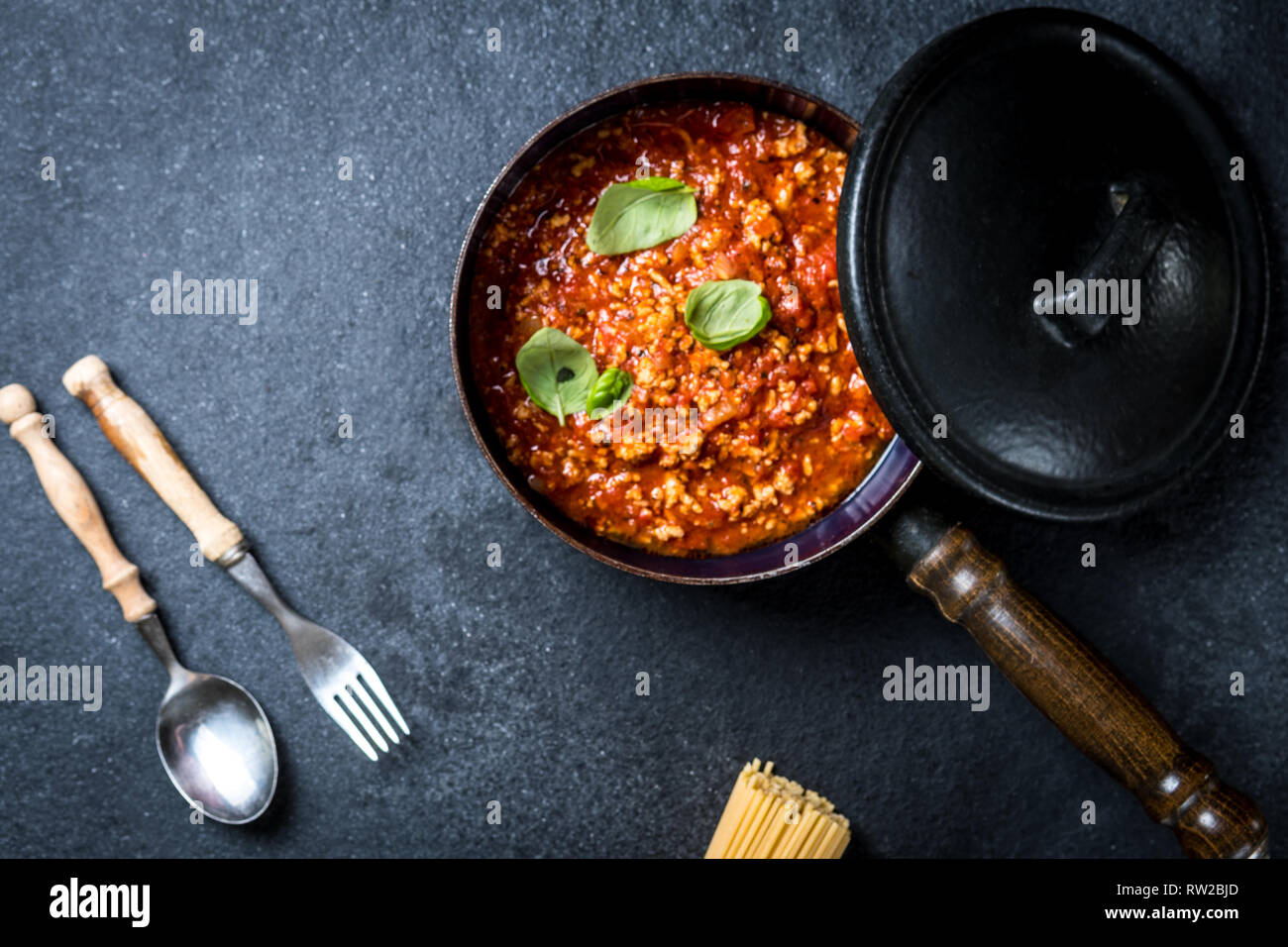 Les pâtes italiennes traditionnelles spaghettis à la bolognaise avec de la viande hachée, tomates, fromage parmesan et basilic sur pierre sombre vue de dessus de table Banque D'Images