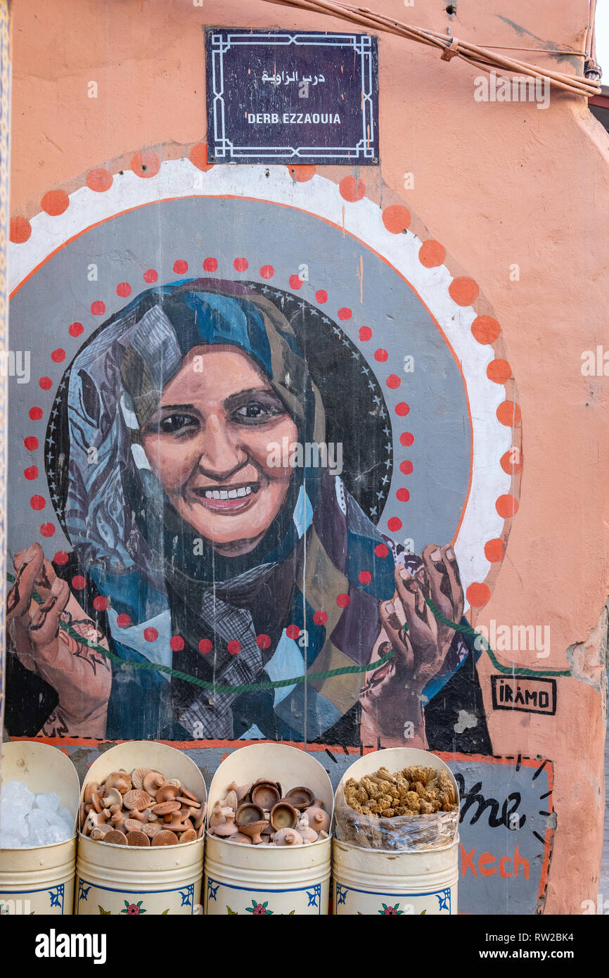 Peinture de femme marocaine sur le mur du bâtiment avec des cases de champignons en face d'elle, Marrakech, Maroc Banque D'Images